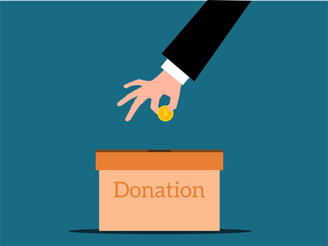 Hand wirft Münze in Spendenbox